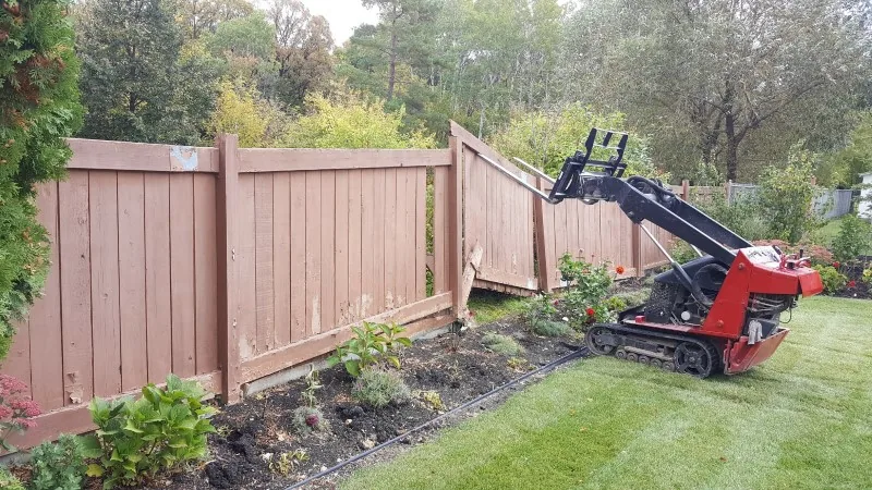 Machine pulling fence posts during a residential removal